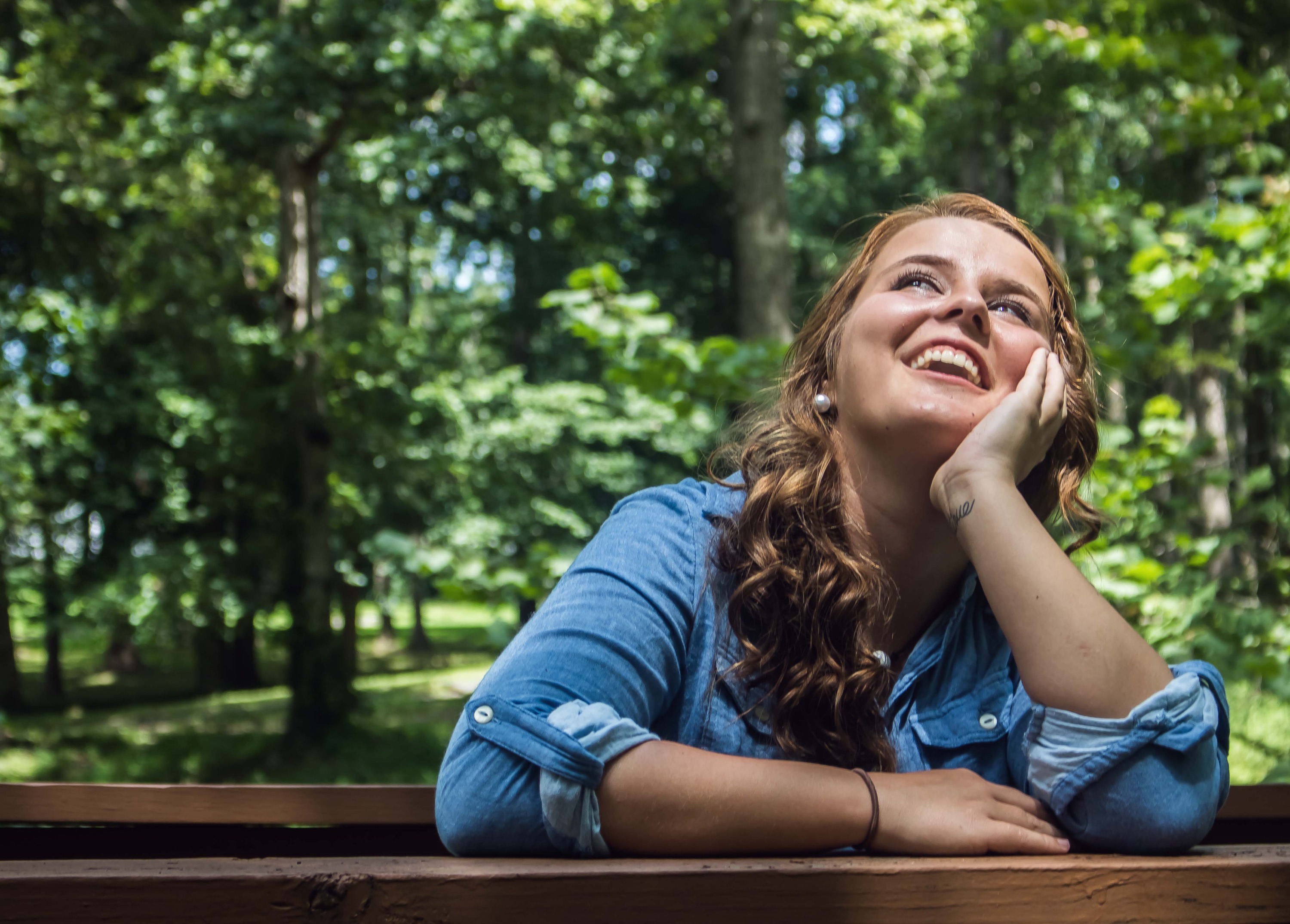 Woman looking up smiling, surrounded by trees